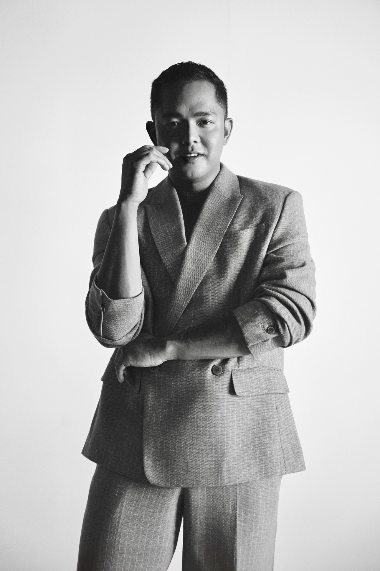 Black-and-white portrait of Patrick in a suit holding paintbrushes