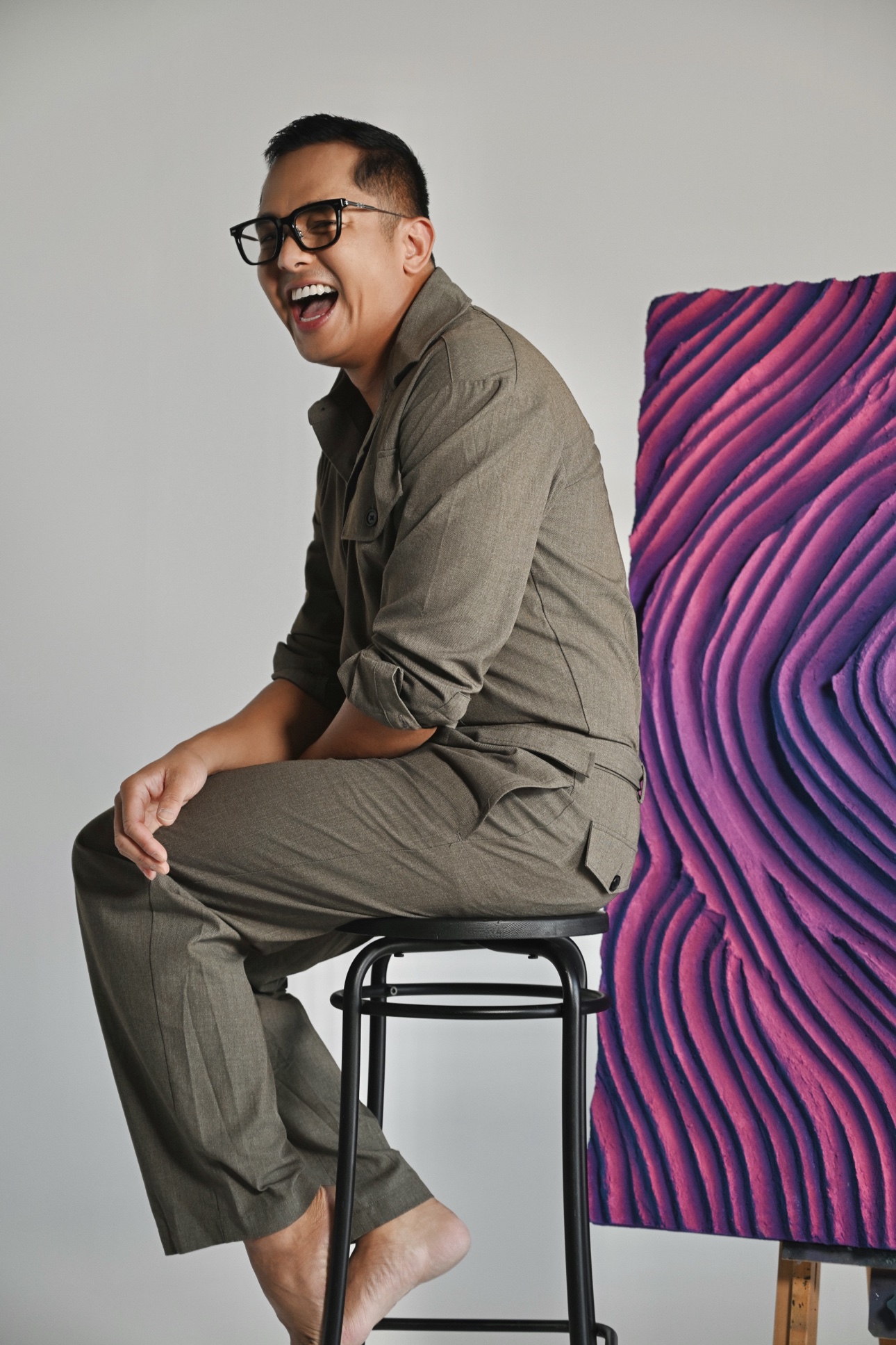 Profile portrait of Patrick laughing in front of a purple relief panel