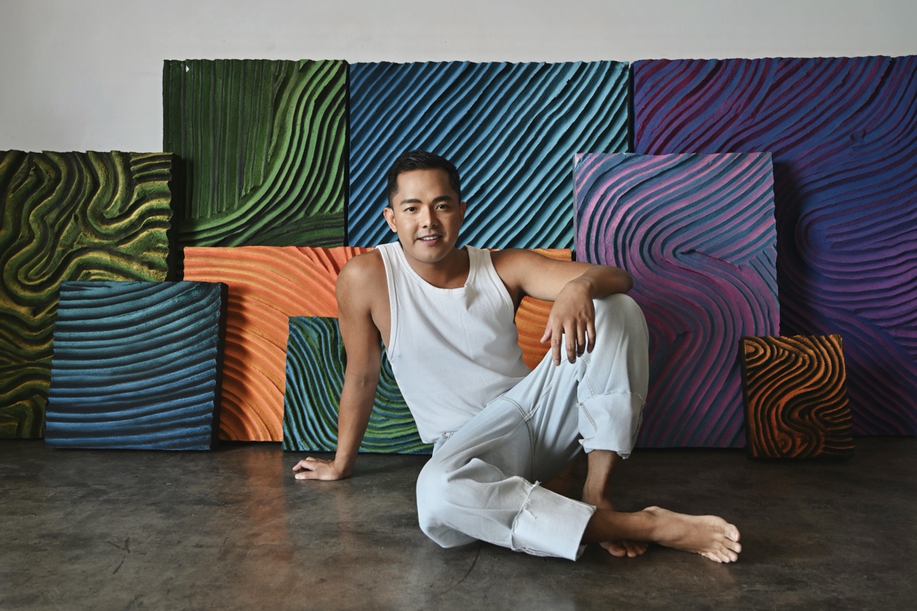 Patrick seated on the studio floor in front of the full collection wall