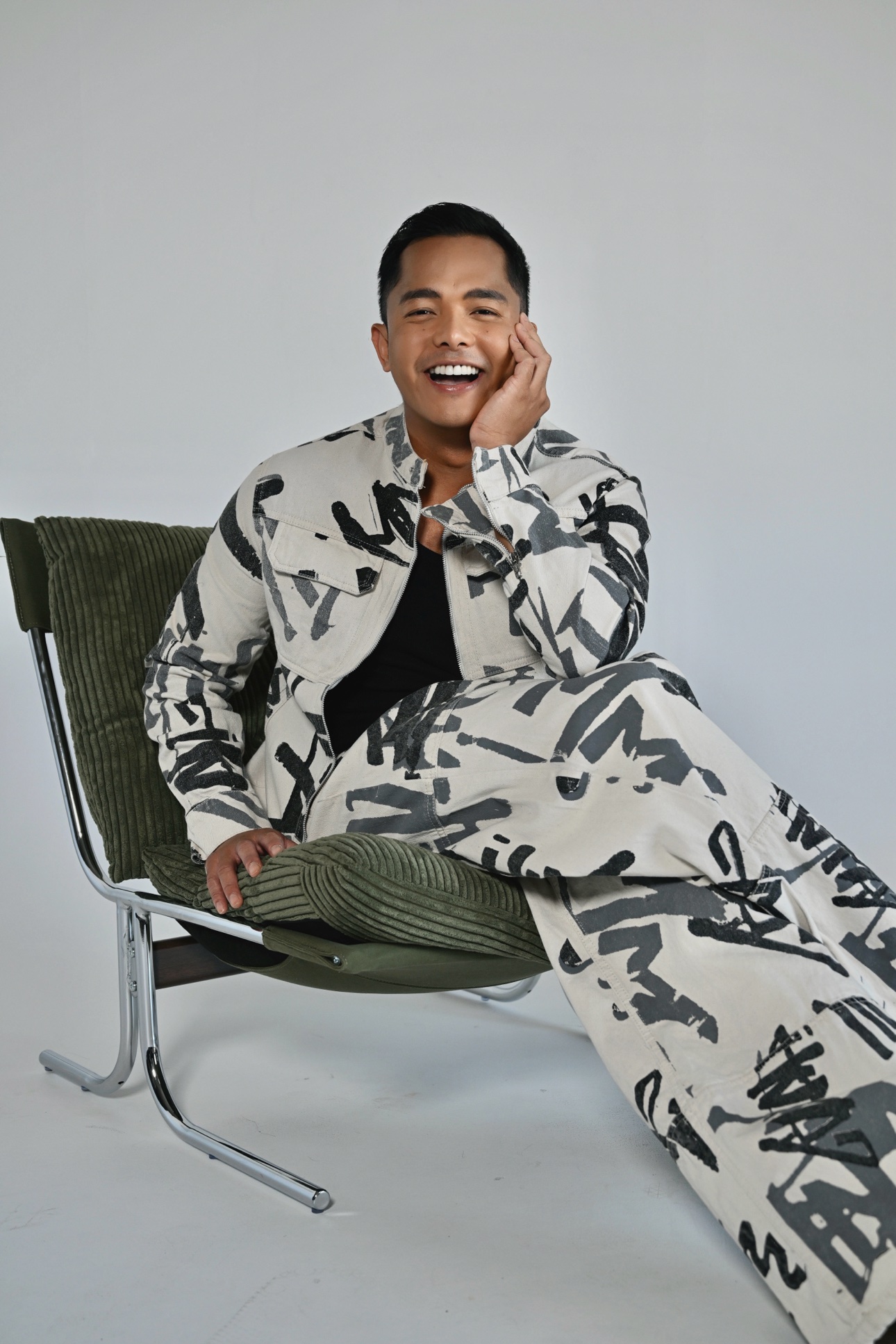 Patrick laughing in a green corduroy chair, wearing the brushstroke print set